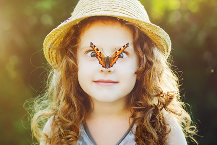 Surprised girl with a butterfly on her nose, focus on a girl's face. Background toning to instagram filter.