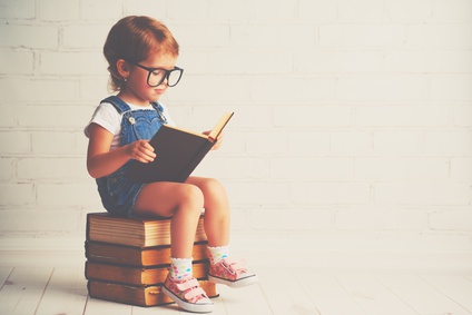 happy child little girl with glasses reading a books