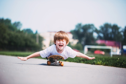 Funny boy on a skateboard. Kid riding skate outdoor. Child practicing outside.